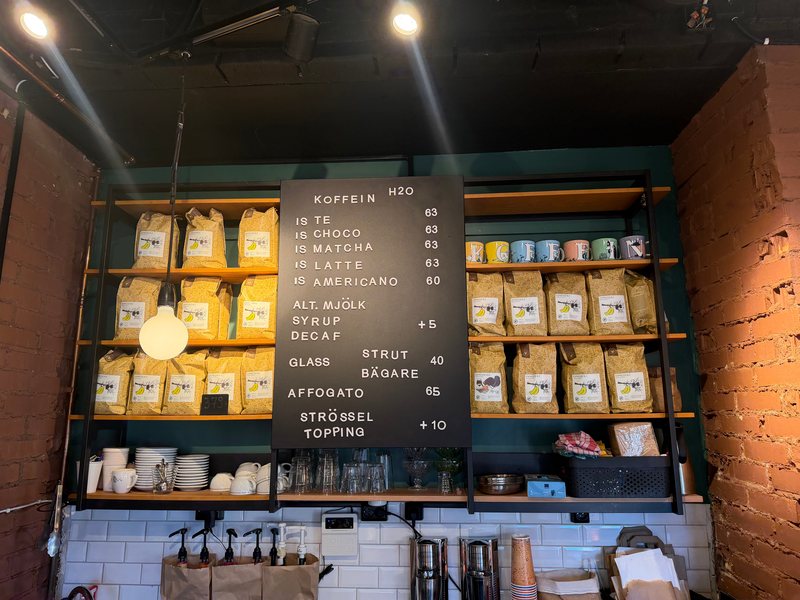 Tavlan med kalla drycker och glass, muggarna och kaffepåsarna på hyllorna