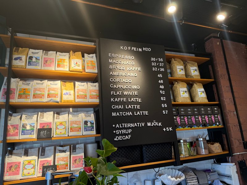 Tavlan med varma drycker och hyllorna med kaffe och te bakom disken